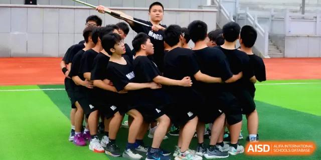 A group of boys in black athletic shirts huddle together, demonstrating teamwork during a sports match at Changsha Mingda Middle School.