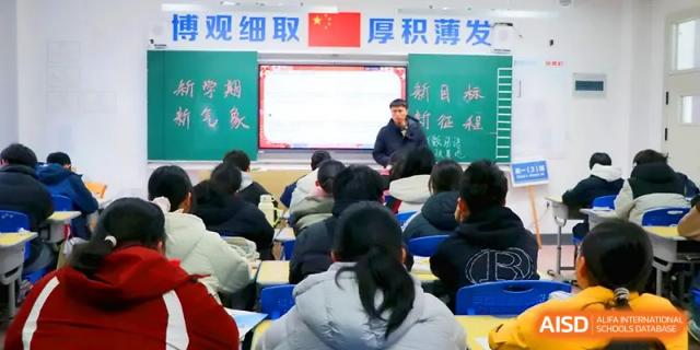 Students in a high school classroom face a large digital whiteboard while an instructor leads a presentation during a core academic session at Walton-Hefei School.
