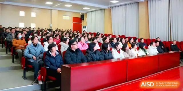 A large audience of parents and students sits in an auditorium with red seating, attentively watching a school presentation at Walton-Hefei School.