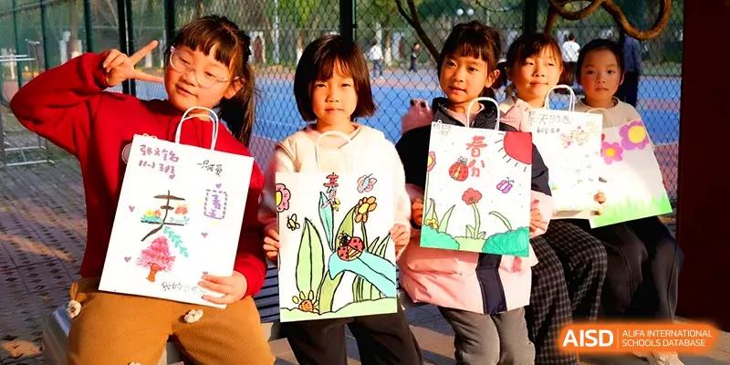 Proud young students display their creative nature-themed drawings during an outdoor art exhibition at Walton-Hefei School.
