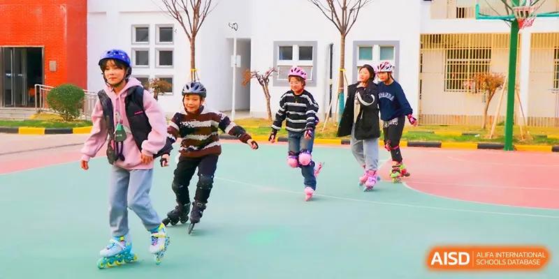 A group of children wearing helmets and safety gear enjoy a roller skating lesson on the school's outdoor rink at Walton-Hefei School.