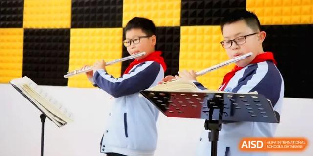 A focused student in a school uniform plays the flute during a music lesson in a specialized rehearsal room at Walton-Hefei School.