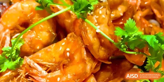Savory glazed chicken pieces garnished with sesame seeds and fresh herbs served for lunch at Walton-Hefei School.