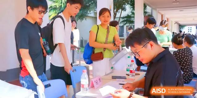 Students and staff gather at a registration desk for an outdoor school community event or sports day at Walton-Hefei School.