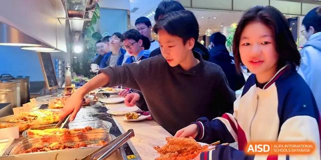 A student reaches for a delicious meal from the self-service buffet in the modern and clean dining hall at Walton-Hefei School.