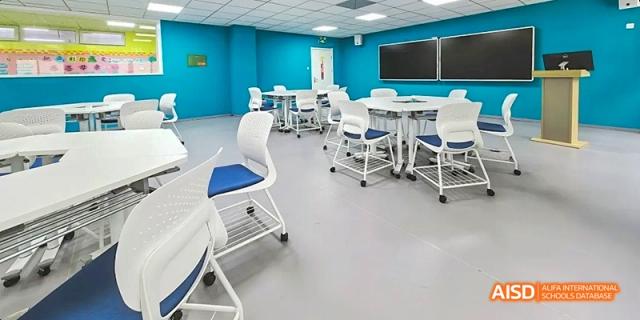 An empty classroom with white tables and chairs at Beijing Limai (International) School.