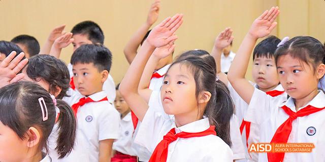 Children at Beijing Limai (International) School raise their hands in a classroom.