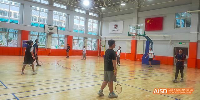 Students at Beijing Limai (International) School play badminton in a gym.