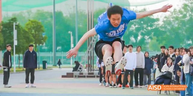 A student at Beijing Limai (International) School jumps over a row of students.