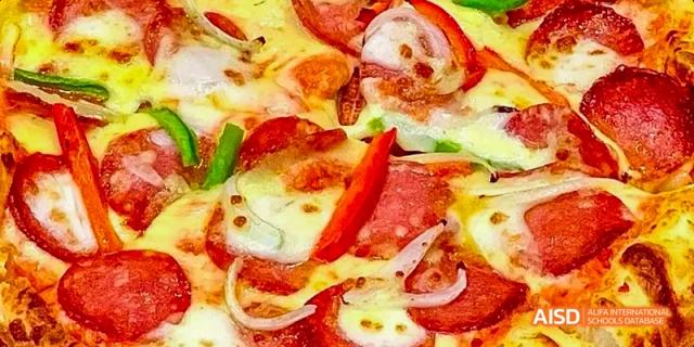 A close-up shot of a pepperoni and onion pizza served at Beijing Limai (International) School.