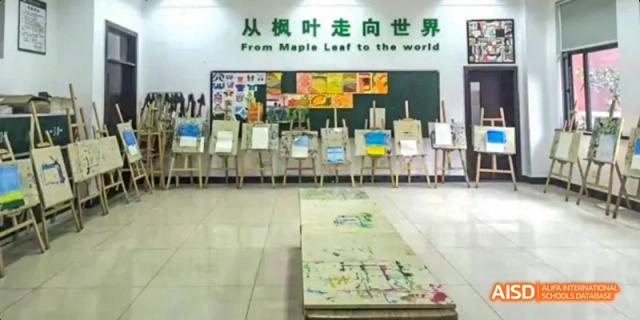 An art room or gallery displaying finished paintings on easels and a long, painted banner on the floor at Maple Leaf International School Chongqing.