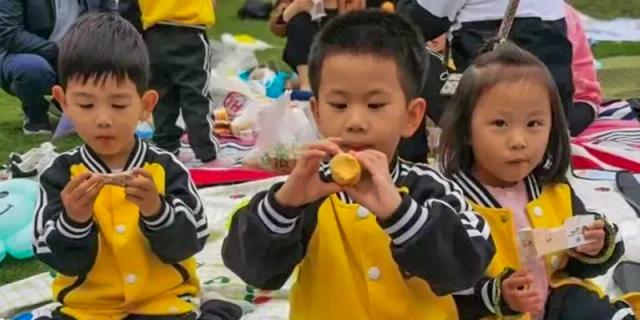 A close-up of a young male student in a yellow shirt eating a piece of fruit during a school event or meal at Maple Leaf International School Chongqing.