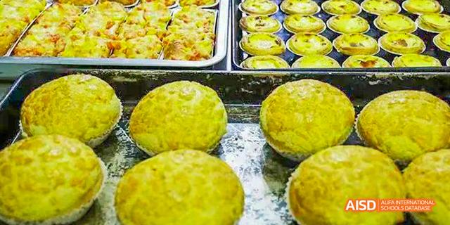 A tray of bright yellow, textured baked goods, possibly sweet buns or pastries, displayed at Maple Leaf International School Chongqing.
