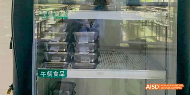A stack of empty, clear food containers visible inside a cabinet or refrigerator at the kitchen or cafeteria of Maple Leaf International School Chongqing.