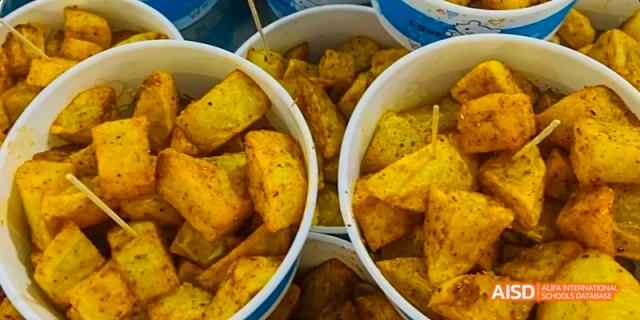 A close-up of deep-fried potato wedges or chunks served in white buckets at Maple Leaf International School Chongqing.