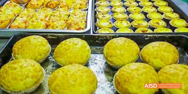 A close-up of a display of egg tarts and bright yellow, textured baked goods at Maple Leaf International School Chongqing.