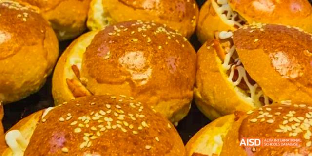 A close-up of golden brown baked sesame seed buns or rolls from the cafeteria at Maple Leaf International School Chongqing.