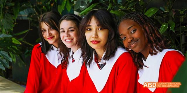 Canadian International School of Beijing female students smiling and posing together in their red and white graduation robes.