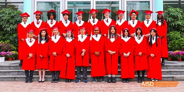 Canadian International School of Beijing graduates in red robes and caps posing for a group photo.