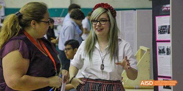 Canadian International School of Beijing student smiling while presenting or speaking in a classroom or event setting.