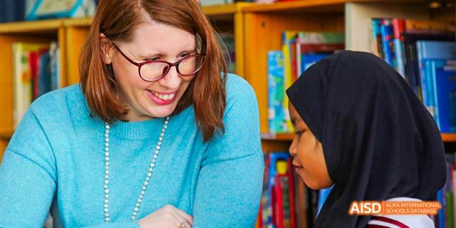 Canadian International School of Beijing teacher and a student in a hijab looking at something together and smiling.
