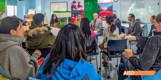 Canadian International School of Beijing students and a teacher listening to a speaker during a presentation in a classroom.