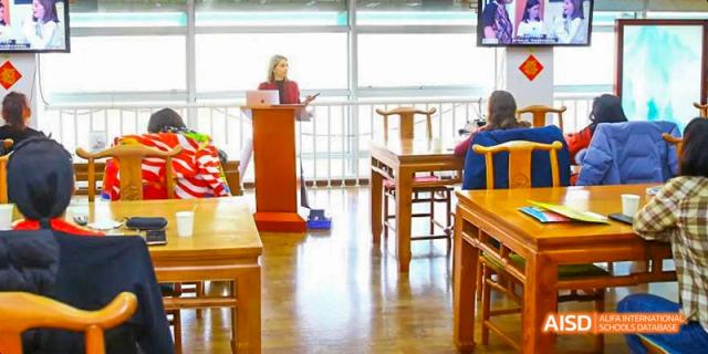 A student speaking at a podium to an audience in a classroom or lecture hall at the Canadian International School of Beijing.