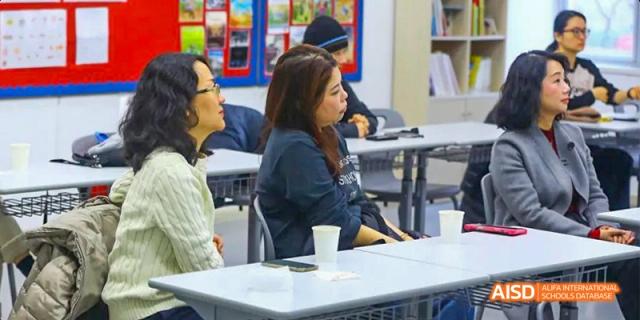 Canadian International School of Beijing students and parents seated at tables, listening to a presentation or attending a meeting.