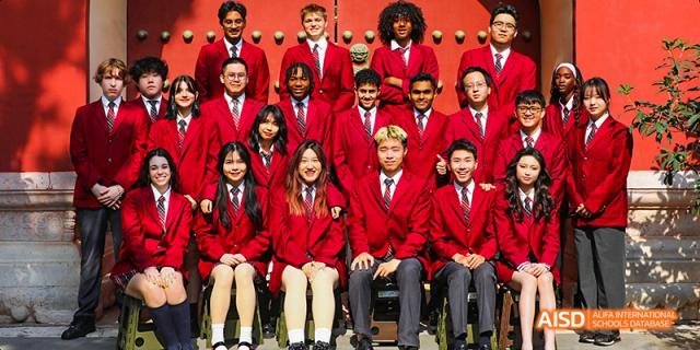 A large group of Canadian International School of Beijing students posing together for a group photo in their red uniforms.