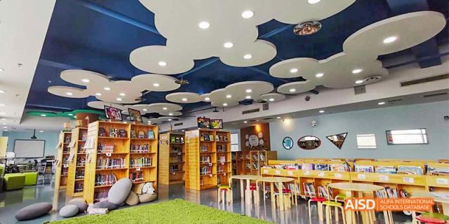 The library at the Canadian International School of Beijing, featuring a unique, cloud-themed ceiling, bookshelves, and various seating options.