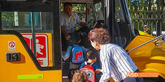 A Canadian International School of Beijing student smiling while boarding a school bus.