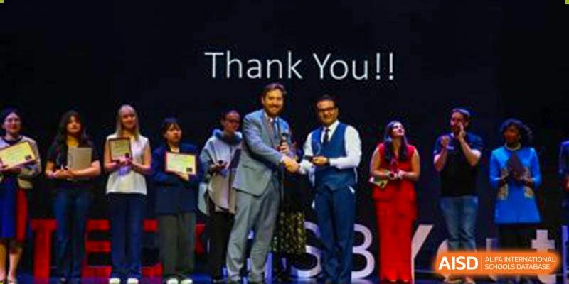 Canadian International School of Beijing students and faculty on a stage at an awards ceremony, with a screen behind them displaying the words "Thank You!!"