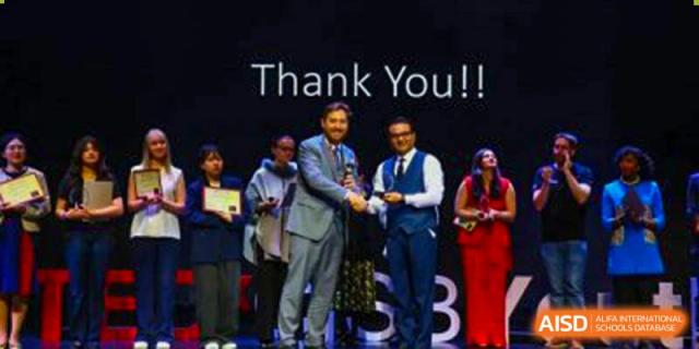 Canadian International School of Beijing students and faculty on a stage at an awards ceremony, with a screen behind them displaying the words "Thank You!!"