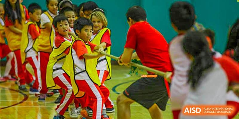 Canadian International School of Beijing students in red and white uniforms participating in a tug-of-war competition.