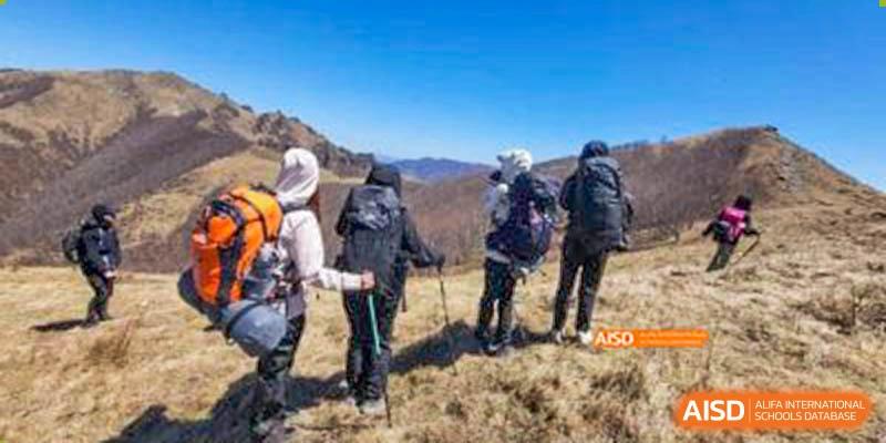 Canadian International School of Beijing students and chaperones hiking on a trail in the mountains, using hiking poles.