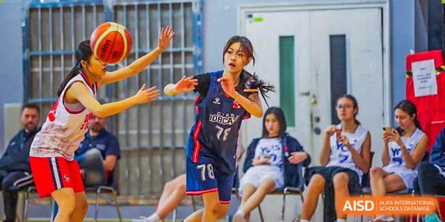 A Canadian International School of Beijing basketball player, wearing glasses and a uniform with the number 71, plays defense during a game.
