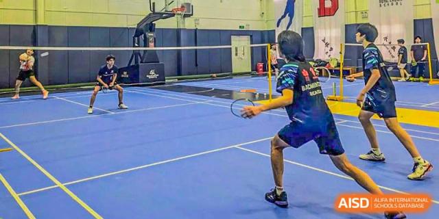 Canadian International School of Beijing students play a game of badminton on an indoor court.