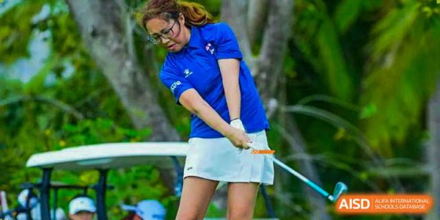 A Canadian International School of Beijing student practices her golf swing on a green outdoor course.
