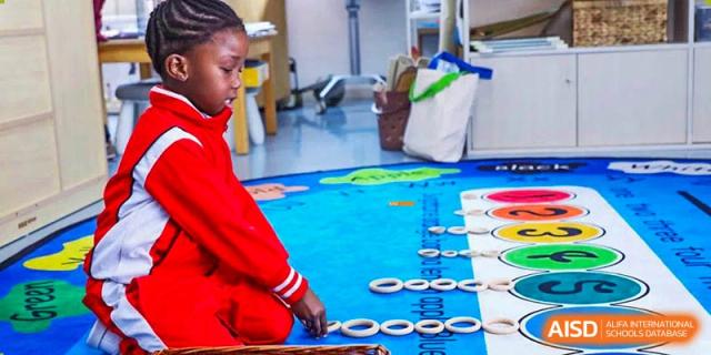 A Canadian International School of Beijing student plays with white tokens on a large world map mat on the floor.