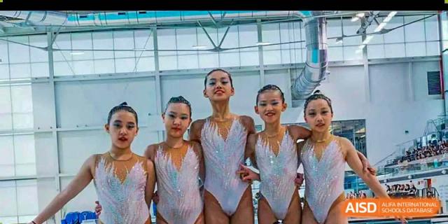 A Canadian International School of Beijing synchronized swimming or gymnastics team poses for a photo in matching sparkly white leotards.