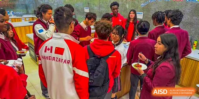 Canadian International School of Beijing students, one of whom is wearing a jacket with "CANADA" on it, serve themselves food from a buffet line.