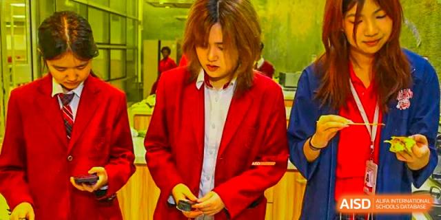 A Canadian International School of Beijing student in a red blazer looking down at a small object in their hands.