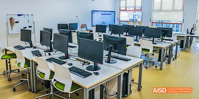 A row of white desks with desktop computers and monitors in a bright computer lab at Fettes College Guangzhou.