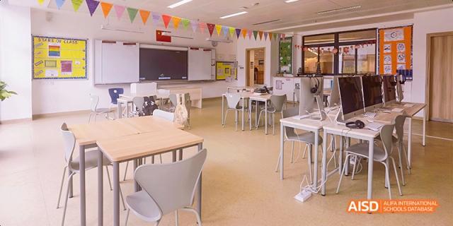A view of a modern classroom or seminar space at Fettes College Guangzhou with flexible seating, a whiteboard, and academic flags.