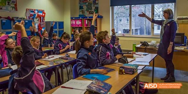 Female students at Fettes College Guangzhou in their dark uniform, attentively working at their desks during a classroom lesson.