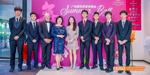 A group of faculty and officials from Fettes College Guangzhou posing for a photo at the "Summer Ball," standing in front of a bright pink backdrop.