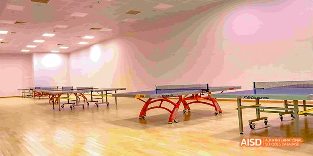 An indoor recreational space at Fettes College Guangzhou with light hardwood floors and two table tennis (ping pong) tables set up for play.