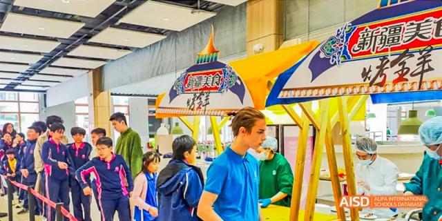Students from Fettes College Guangzhou attending an international or cultural fair with colorful market stalls and distinctive architecture.