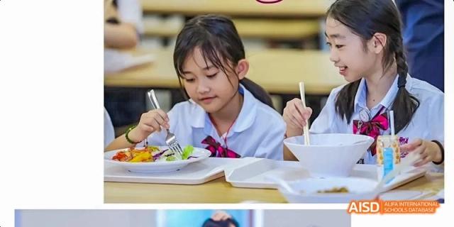 A young female student at Fettes College Guangzhou in a school uniform eating a healthy meal with a fork and knife at a dining table.