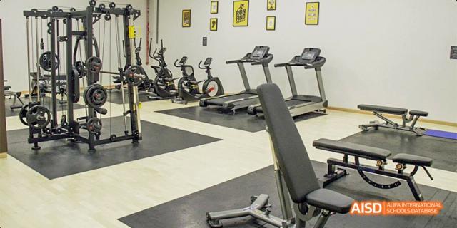 A view of the school fitness center at Fettes College Guangzhou, equipped with several treadmills, exercise bikes, and a weight bench.